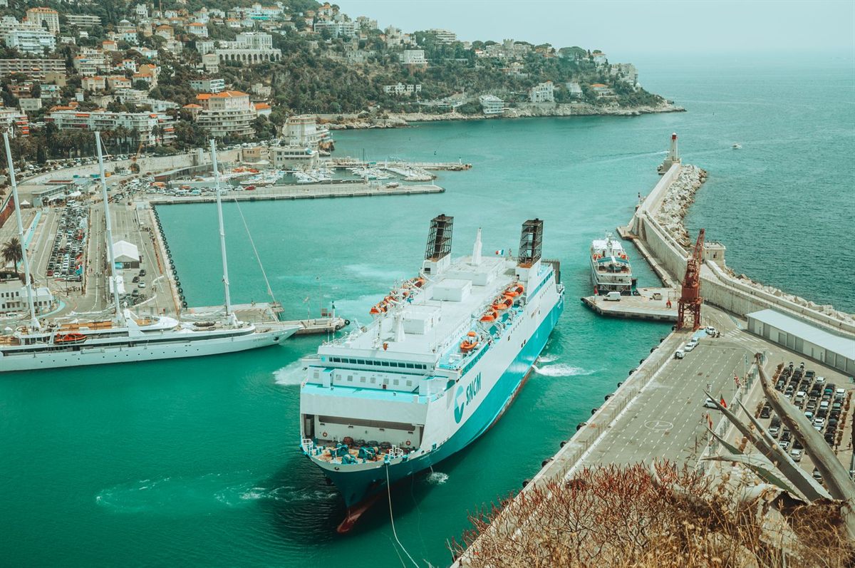 Ferry and yachts in a harbor below a hillside town